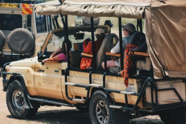 Wide-angle view of a safari vehicle crossing open East African savannah during a multi-country safari.