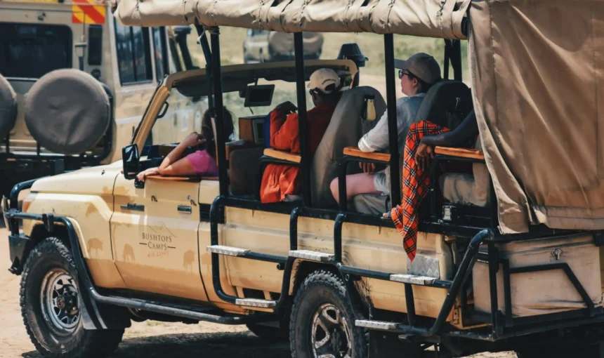Wide-angle view of a safari vehicle crossing open East African savannah during a multi-country safari.