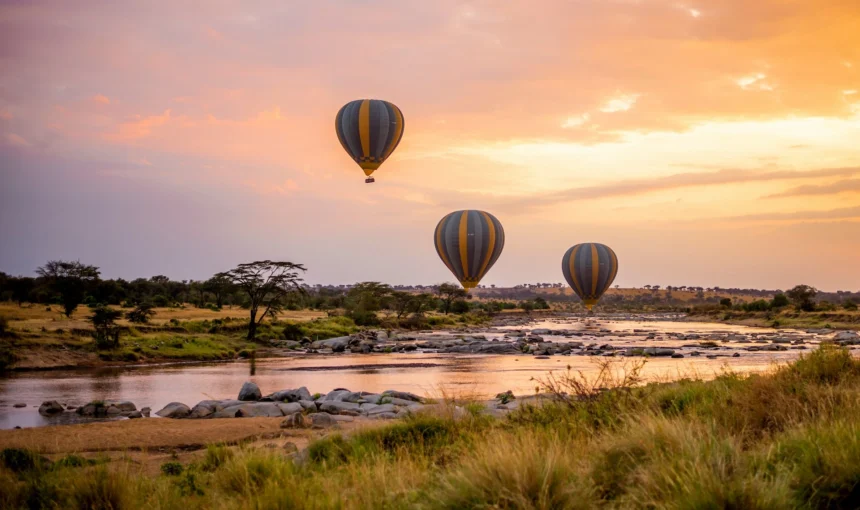 Wide-angle view of hot air safari baloons on open East African savannah grassland.